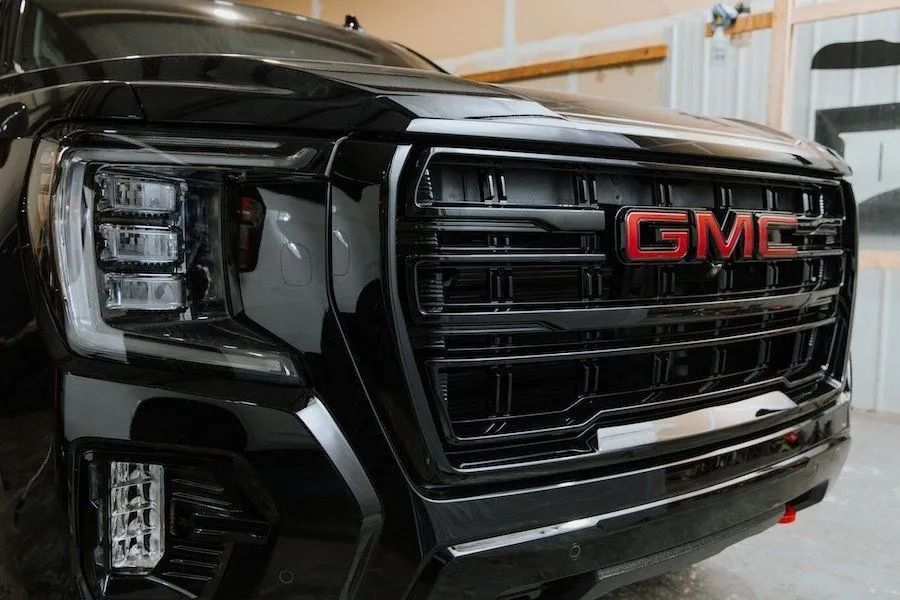 Black GMC SUV front grille and headlights in a garage