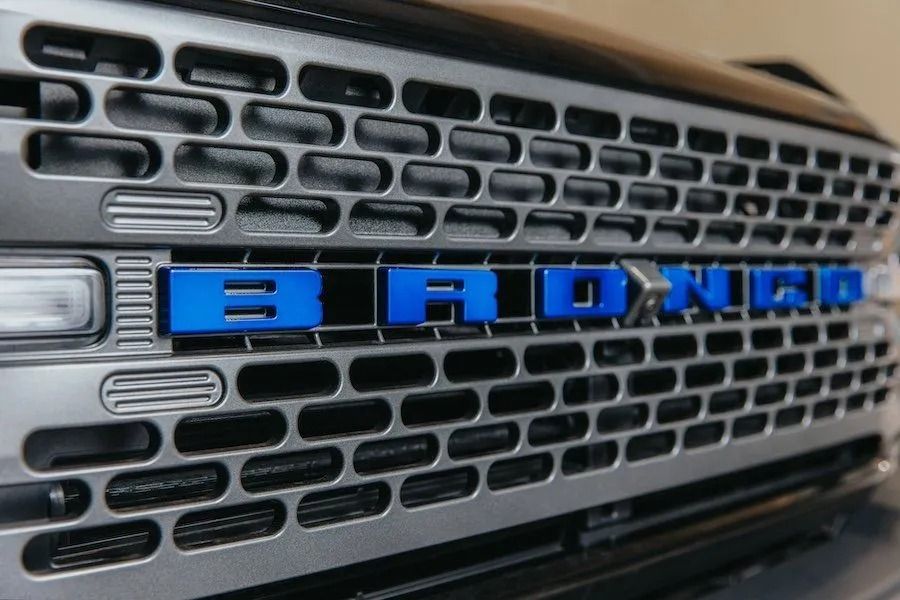 Close-up of a black truck grille with blue “BRONCO” lettering.