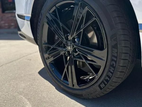 Close-up of a black alloy wheel and Michelin tire on a car parked on pavement