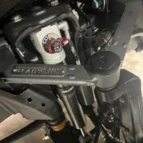 Close-up of a motorcycle handlebar and front fork assembly, with a metallic clamp and black components.