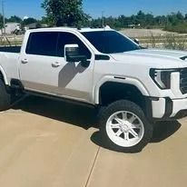 White lifted pickup truck parked on a road under a clear sky