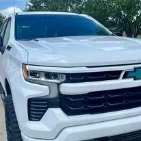 White Chevrolet SUV front view parked outdoors with a teal bowtie emblem