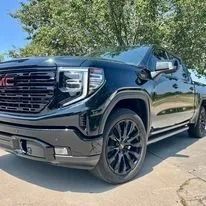Black GMC pickup truck parked outdoors on a driveway, front-left view