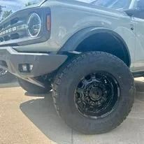 Lifted gray SUV with oversized off-road tire and black wheel parked on concrete
