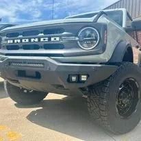 Modified gray Ford Bronco SUV with off-road tires parked outdoors in sunlight