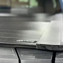 Close-up of a black vehicle roof rack bar with silver trim and visible branding on the roof.