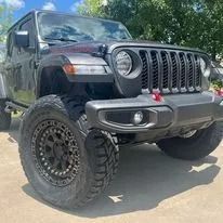 Black Jeep Wrangler with lifted suspension and off-road tires parked outdoors.