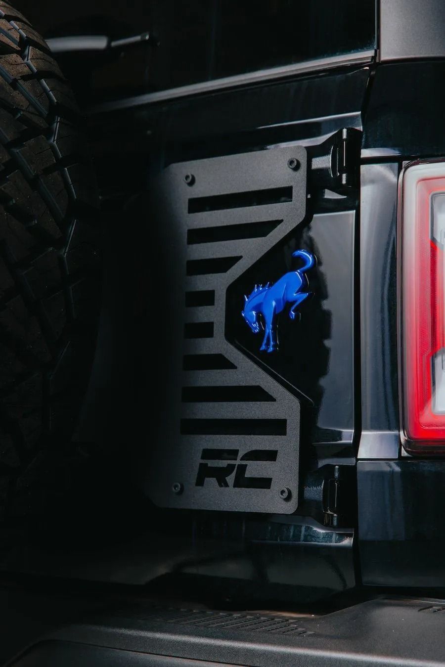 Close-up of a black off-road vehicle with a metal side step and a red taillight.
