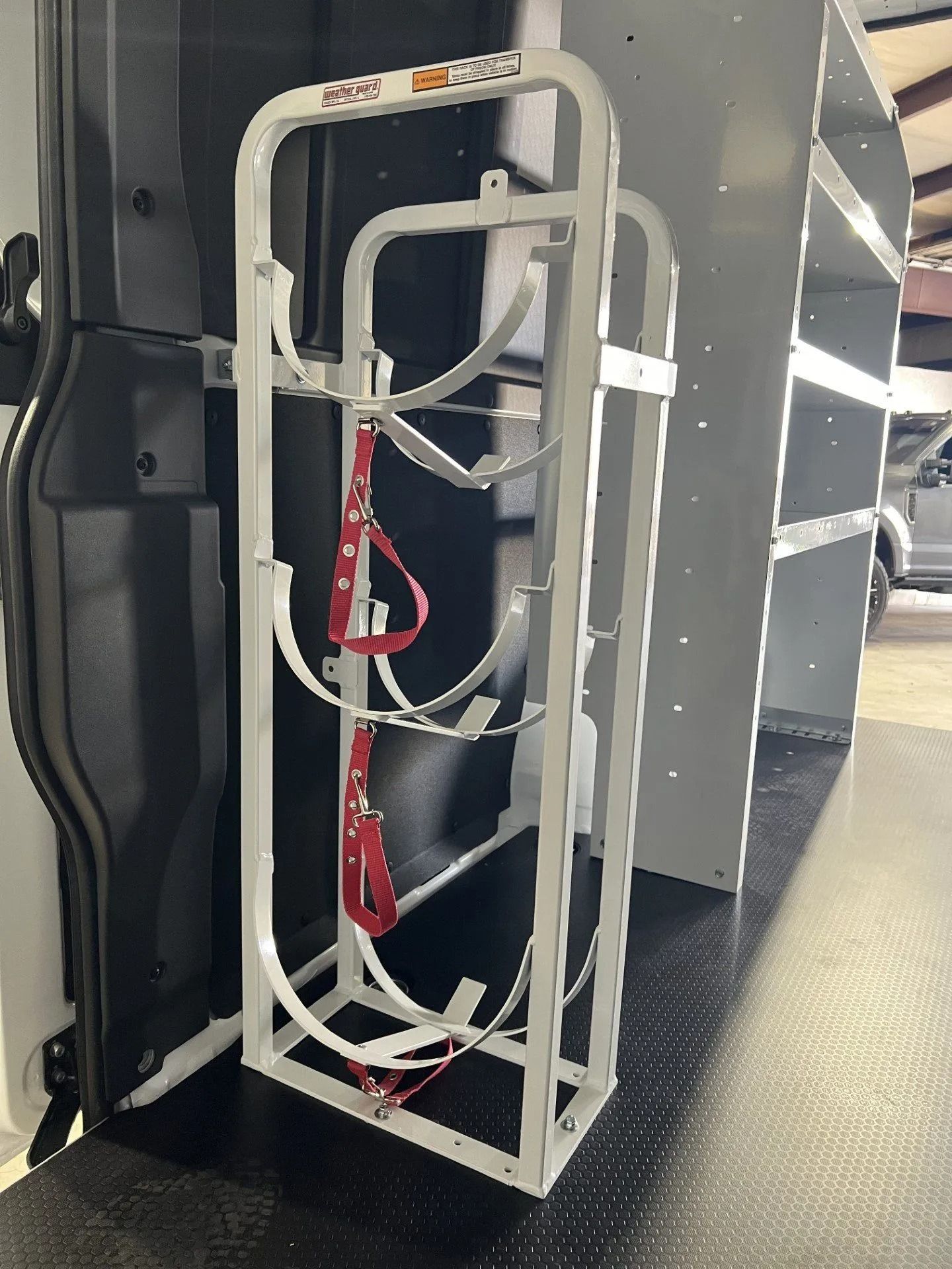 Collapsed white folding hand truck with red straps in an industrial corridor