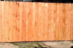 A wooden fence is sitting on the side of a road.