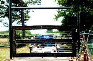 A car is parked in a field behind a gate.