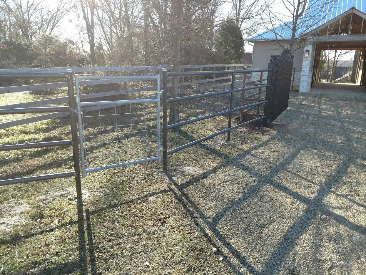 A metal fence is sitting in the grass in front of a garage.