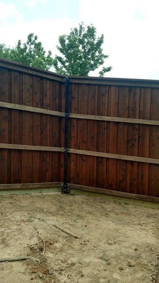 A wooden fence is sitting in the middle of a dirt field.