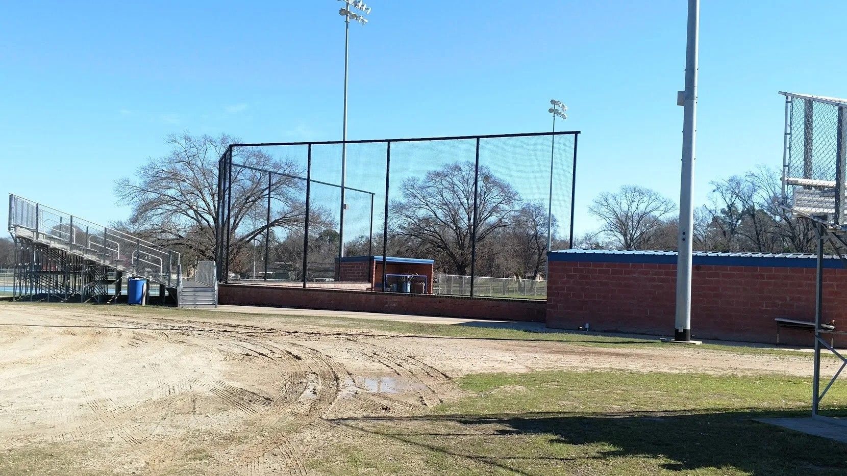 A baseball field with a fence and bleachers in the background