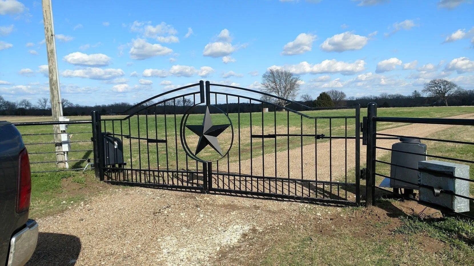 A car is parked in front of a gate with a star on it.