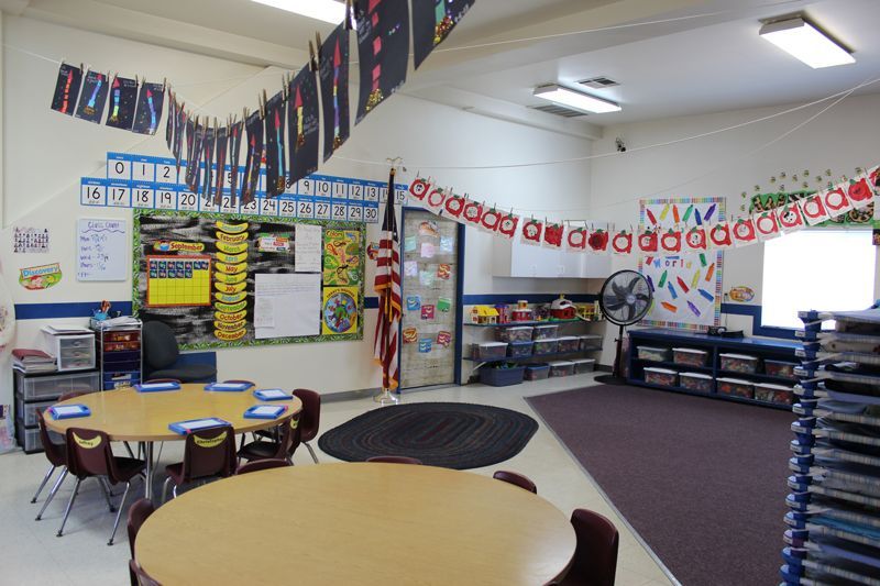A classroom with tables and chairs and a flag hanging from the ceiling