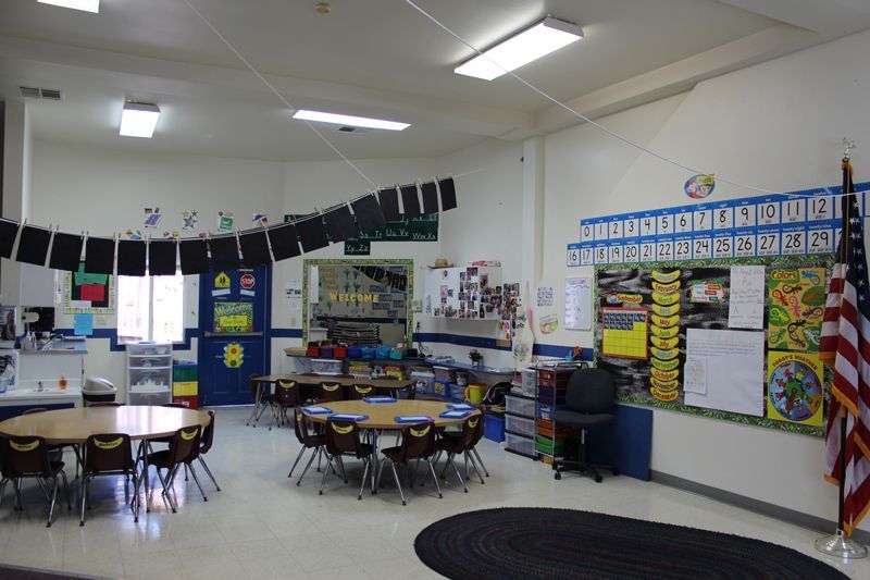 A classroom with tables and chairs and an american flag