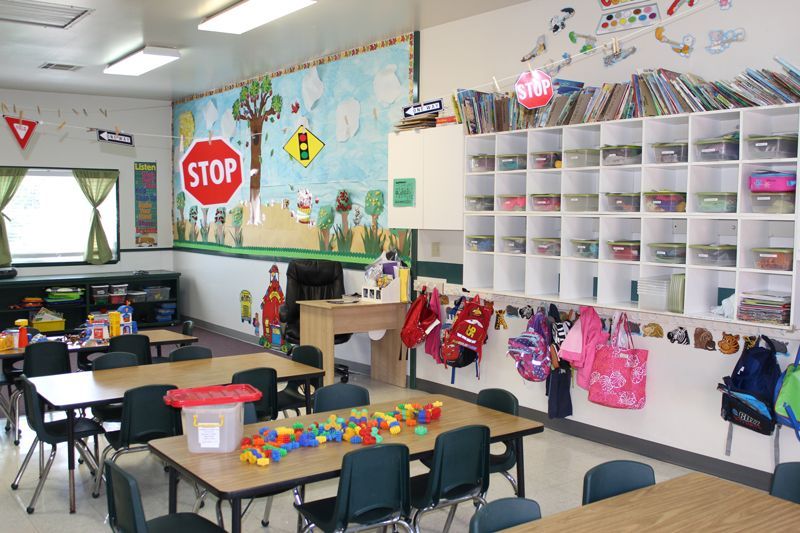 A classroom with tables and chairs and a stop sign on the wall