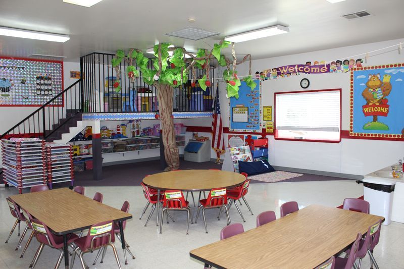 A classroom with tables and chairs and a sign that says welcome