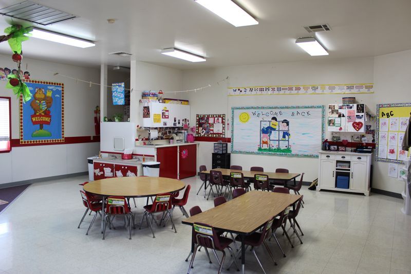 A classroom with tables and chairs and a whiteboard that says abc