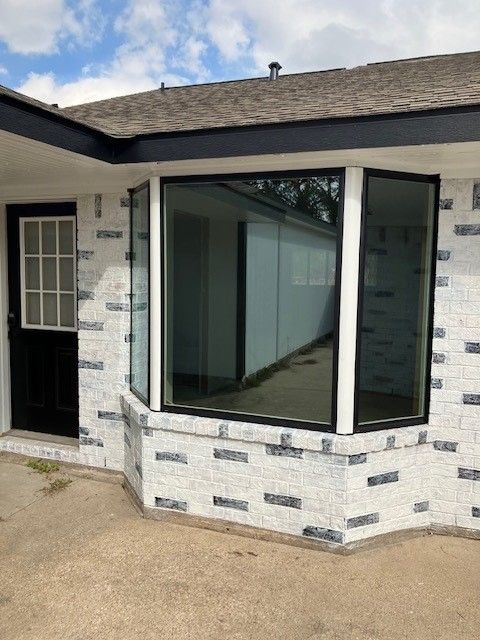 A white brick house with a large window and a black door.