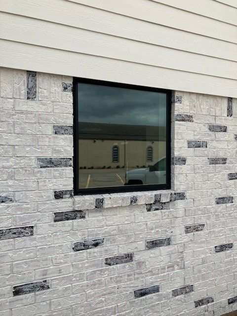 A white brick wall with a black window on it.