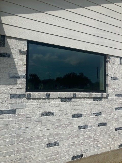 A white brick wall with a large window on it.