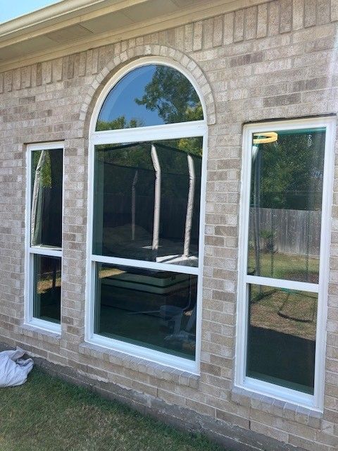 A brick house with arched windows and a trampoline in the backyard