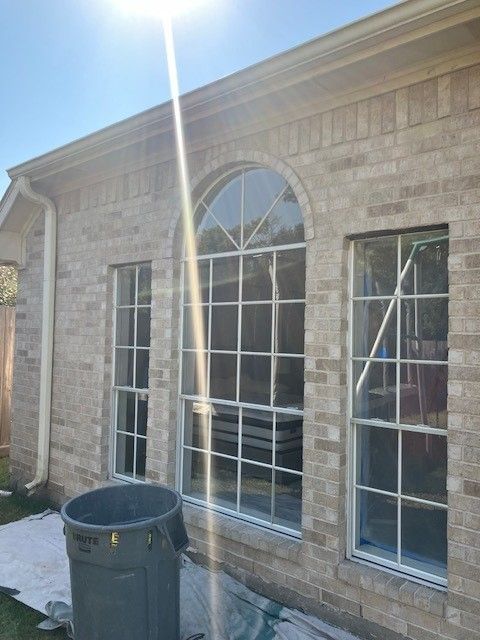 A brick house with a large window and a trash can in front of it