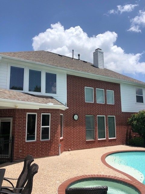 A man is standing in front of a house next to a pool