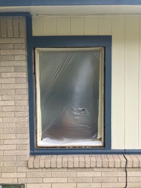 A brick building with a window covered in plastic.