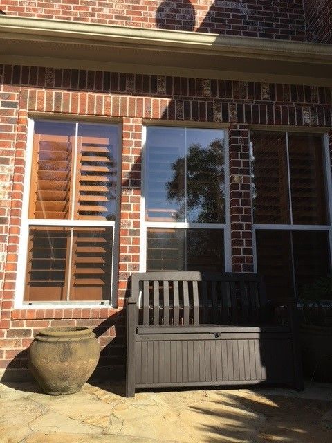 A brick building with shutters on the windows and a bench
