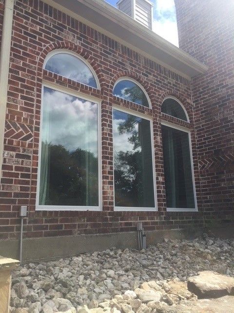 A brick building with three arched windows and a pile of rocks in front of it.