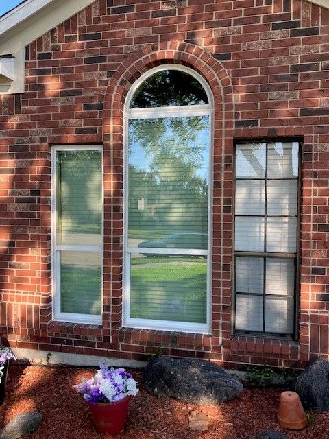 A brick house with arched windows and a potted plant in front of it