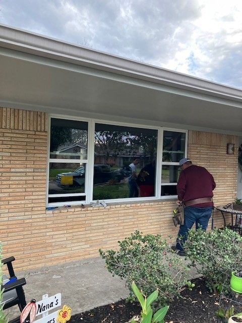 A man is cleaning a window on a brick house.