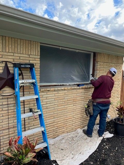 A man is working on a window on a brick house