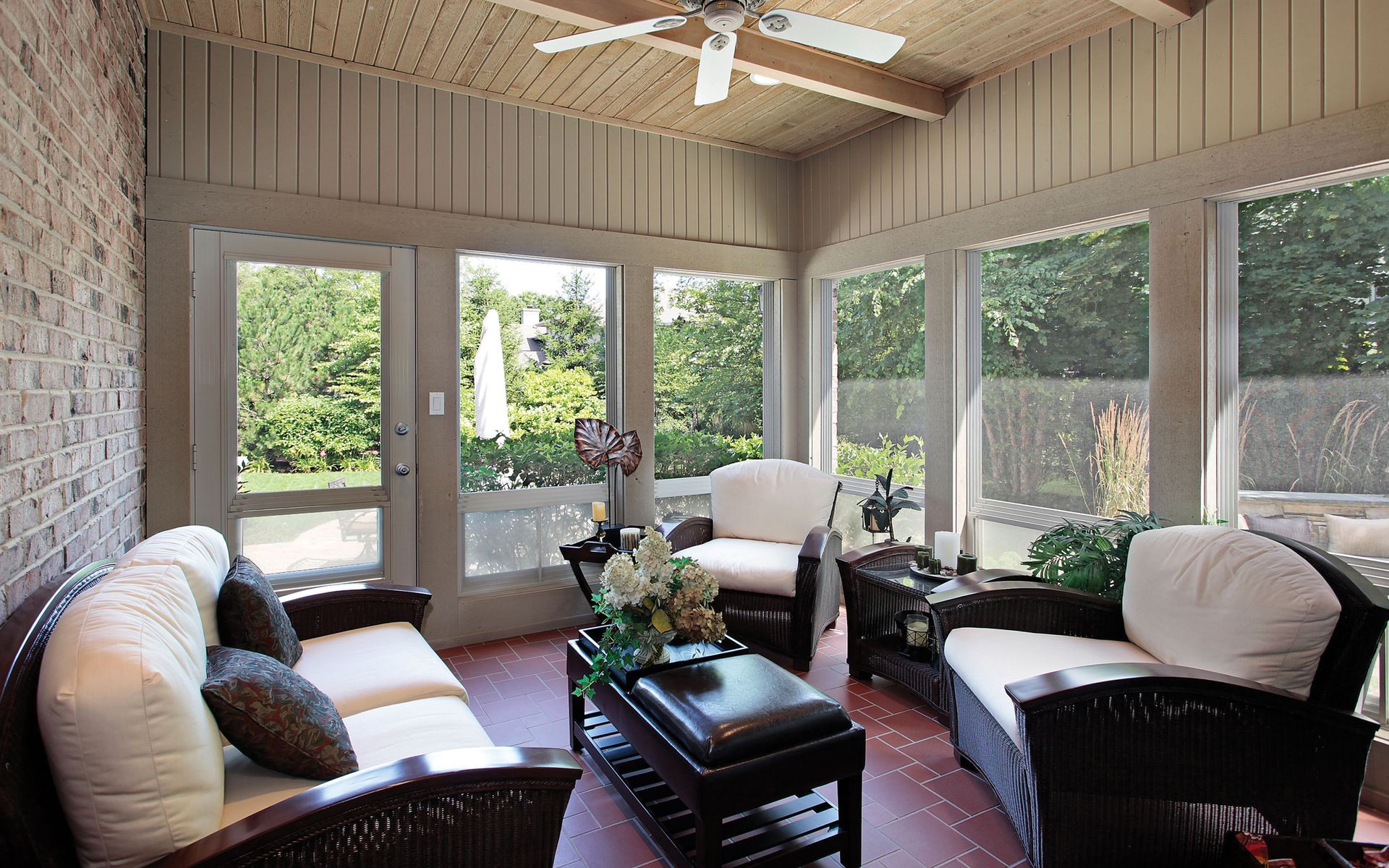 A living room with a couch , chairs , a table and a ceiling fan.