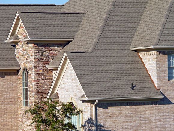 A brick house with a gray roof and a chimney