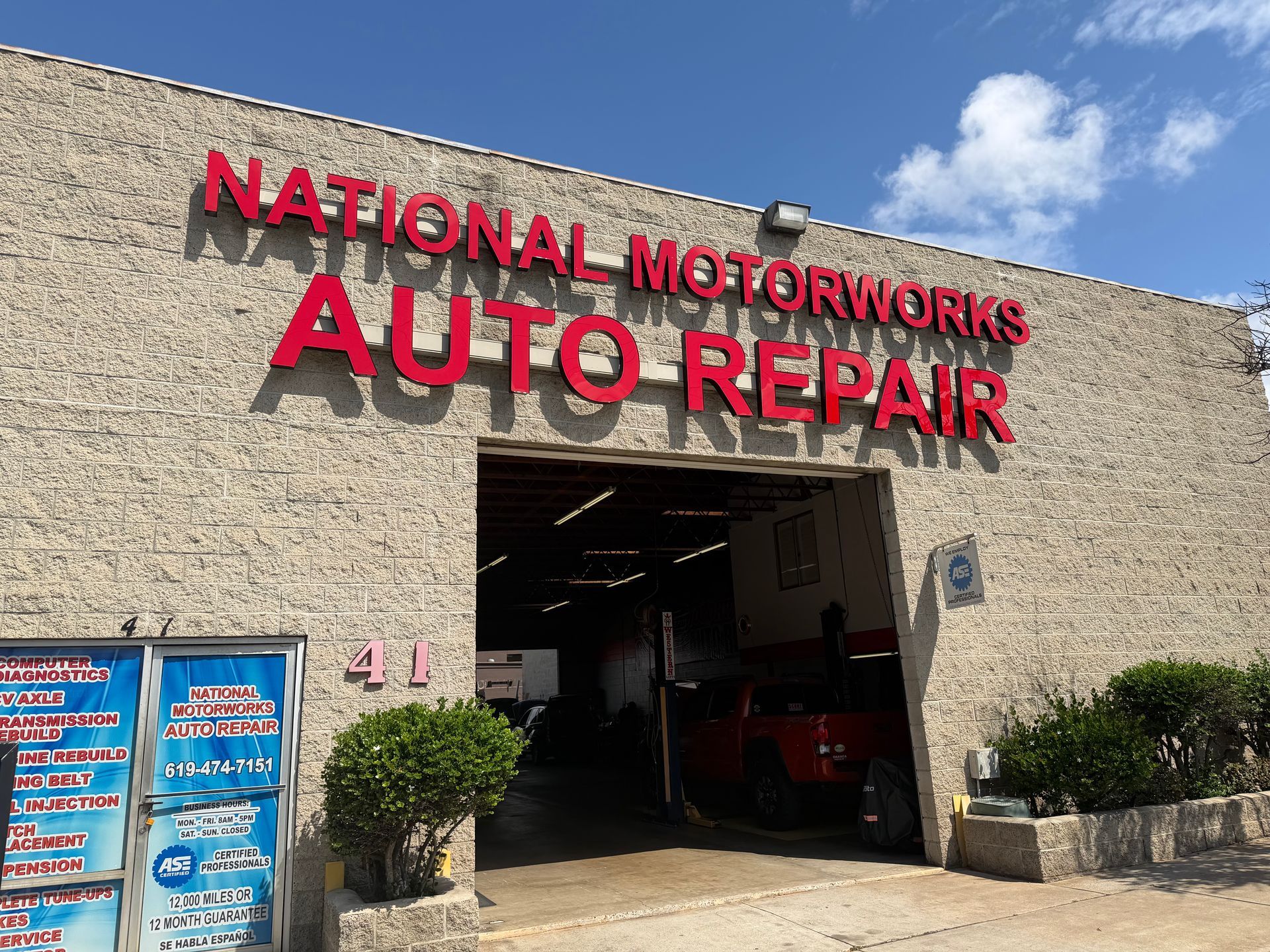 The storefront of National Motorworks Auto Repair, featuring large red lettering on a beige textured facade.