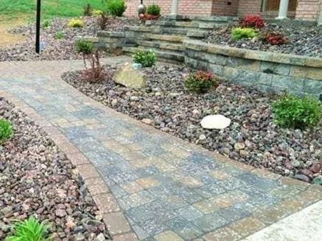 Brick pathway curves through a landscaped garden with rock beds and retaining walls.
