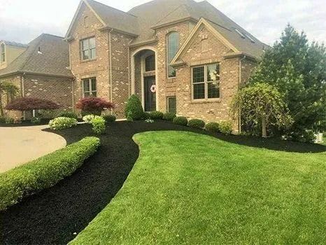 Brick house with green lawn, black mulch, and manicured landscaping.