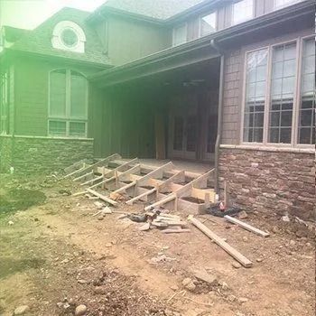 Exterior of a house under construction; steps with wooden framing, dirt ground.