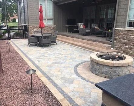 Outdoor patio with brick pavers, fire pit, dining set, and seating under a covered porch.
