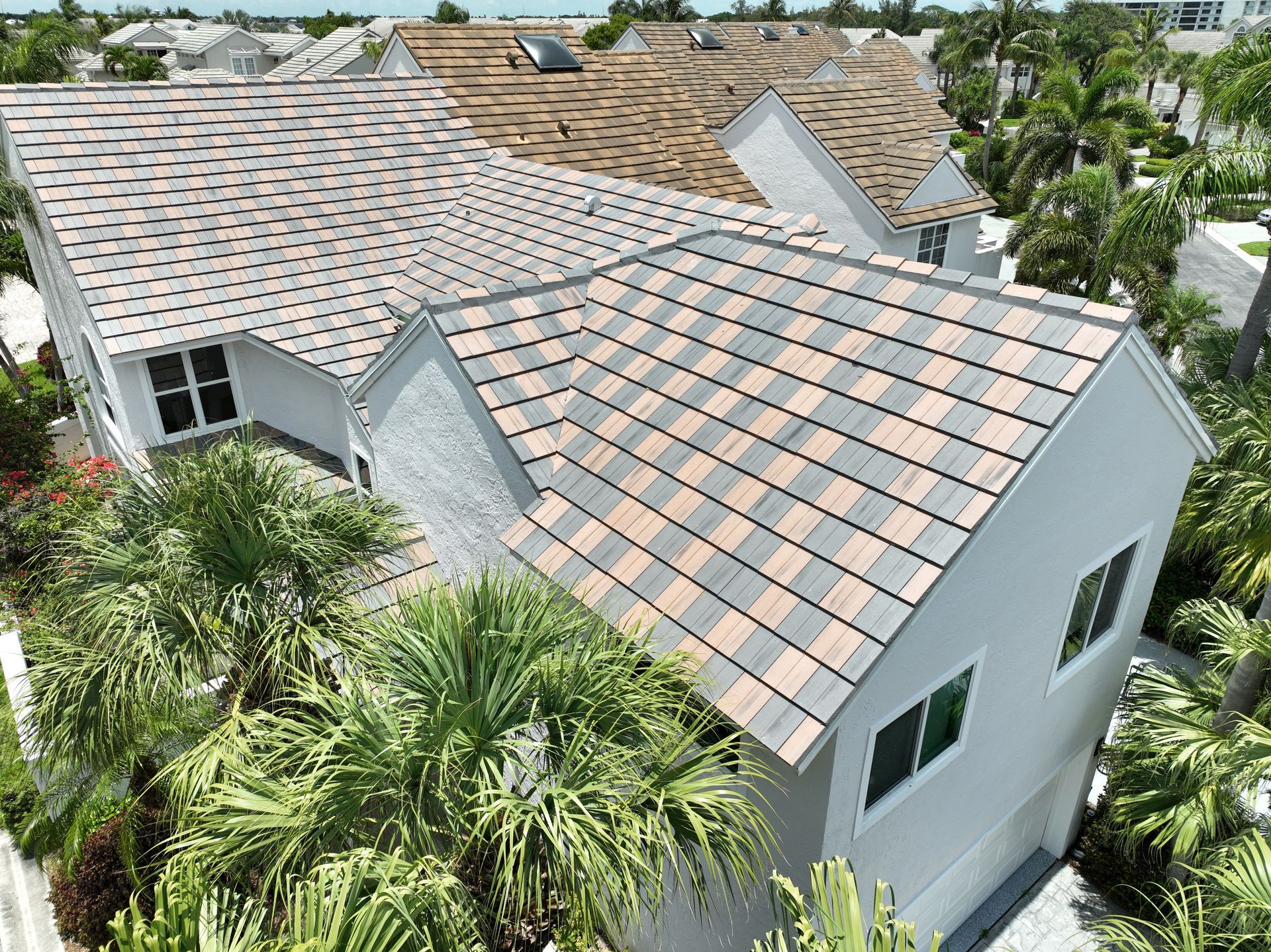 House with gray and brown tiled roof, surrounded by palm trees.