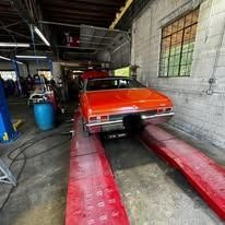 A red car is sitting on a lift in a garage.