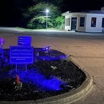 A blue light is shining on a sign in a parking lot at night.