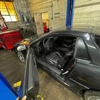 A black car is parked in a garage with the door open.