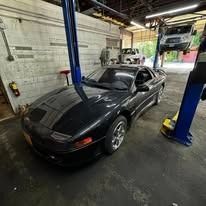 A black car is sitting on a lift in a garage.