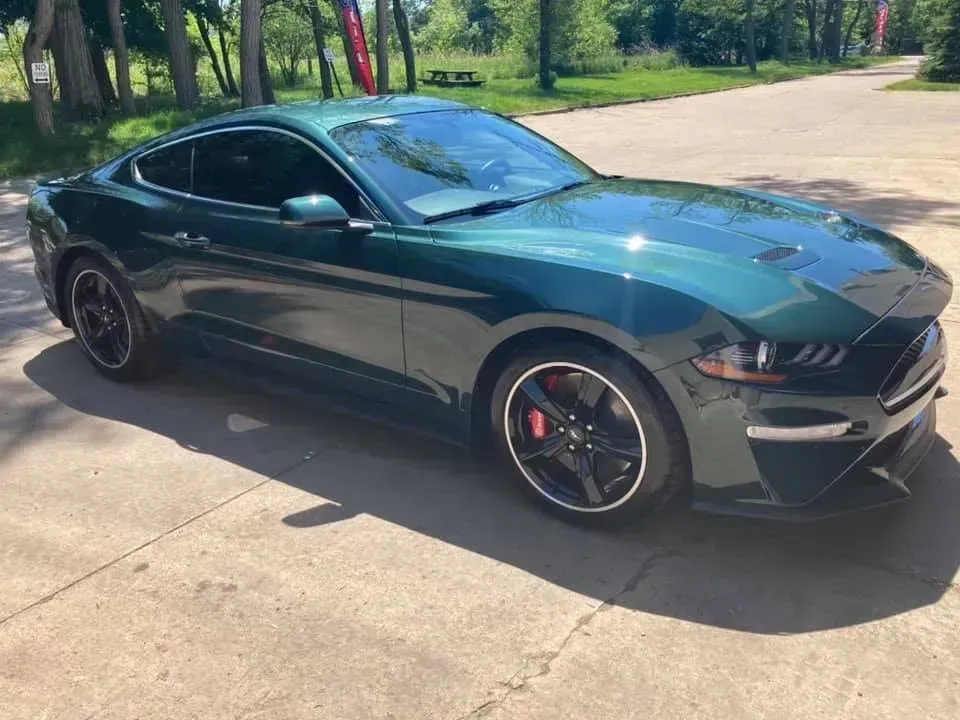 Green Ford Mustang parked on a concrete surface.