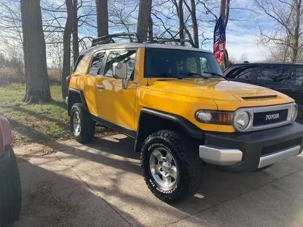 Yellow Toyota FJ Cruiser SUV parked outdoors with a roof rack.